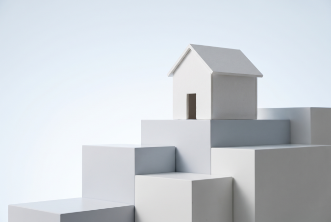 Small white model home on ascending geometric steps with "Loan Limits Explained" text, representing different mortgage loan limit tiers